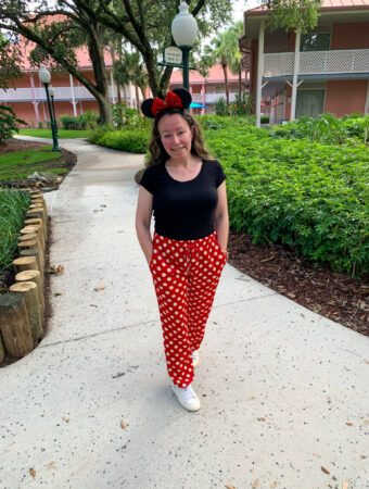 woman wears Minnie Mouse polka dot trousers with mouse ears at Disney World on way to Magic Kingdom