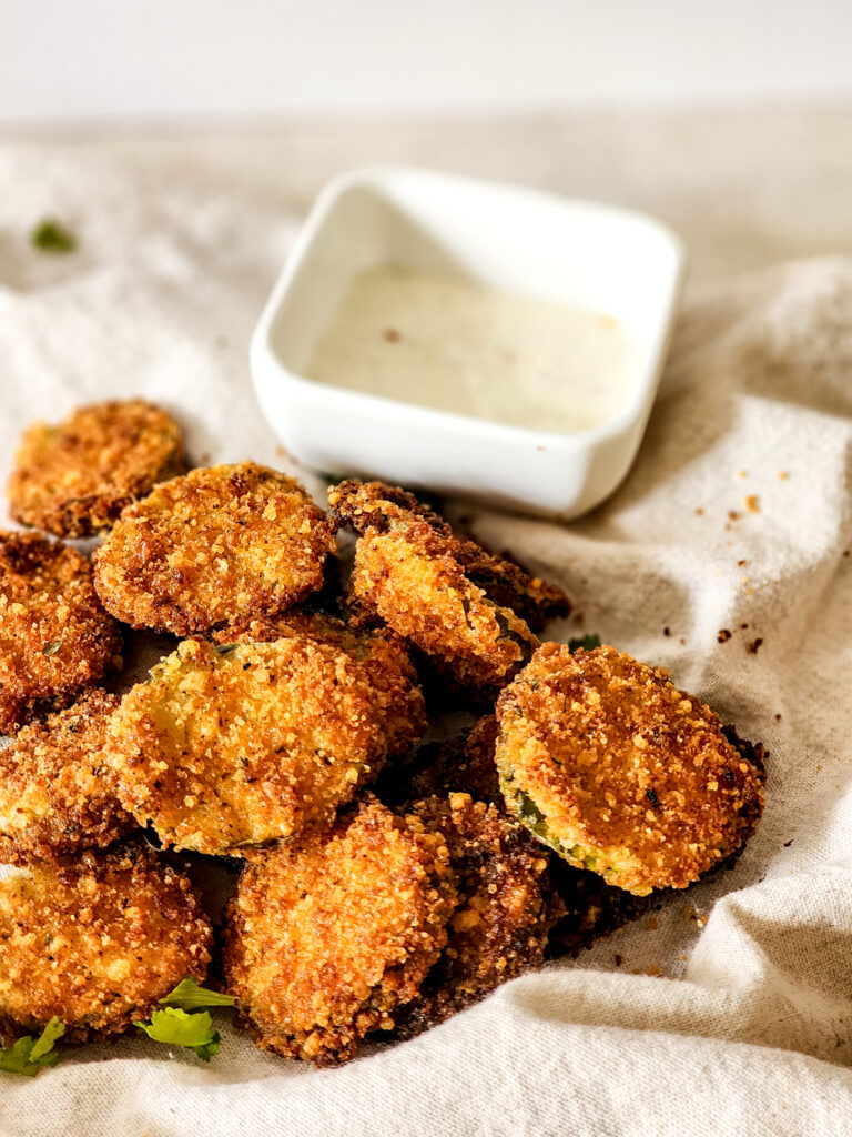 parmesan fried pickles with ranch dipping sauce in back in white bowl