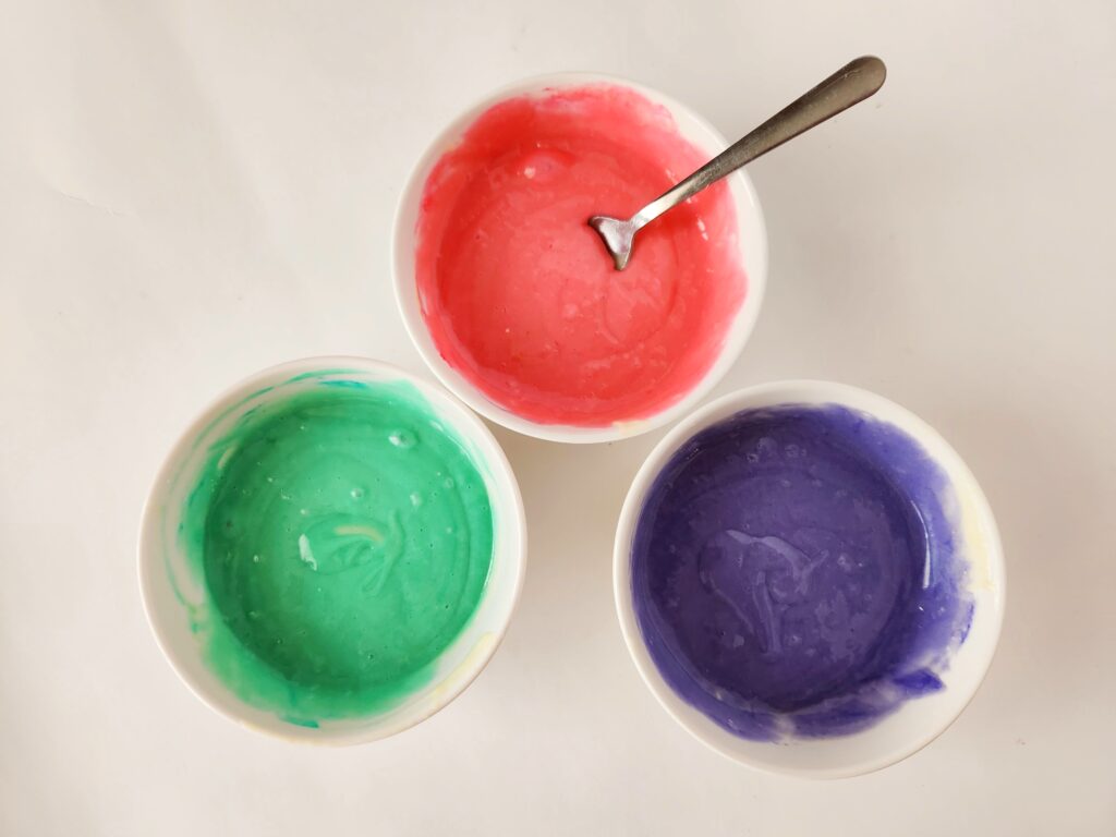 three bowls of cake batter with food coloring