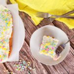rainbow cake with food coloring and sprinkles beside yellow napkin