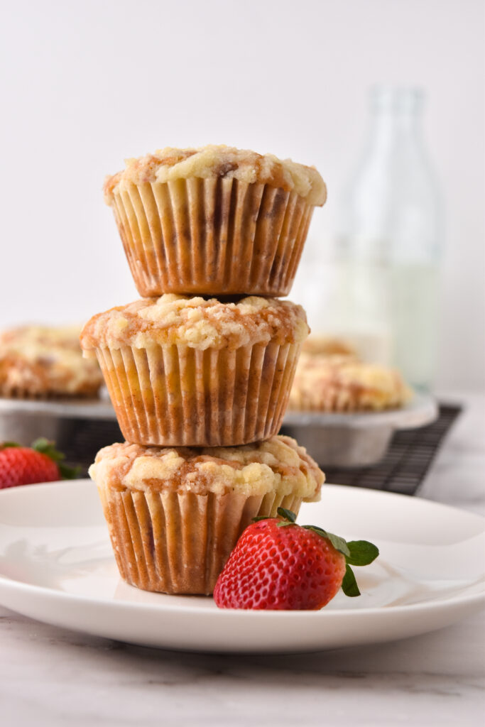 strawberry crumble muffins stacked on saucer with strawberry to side