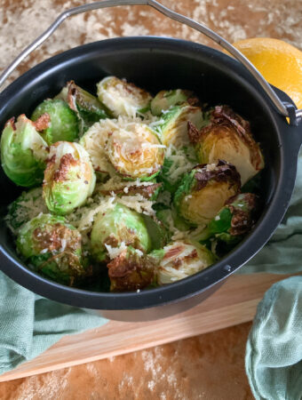 air fryer skillet of air fried Brussels sprouts on cutting board with cloth next to