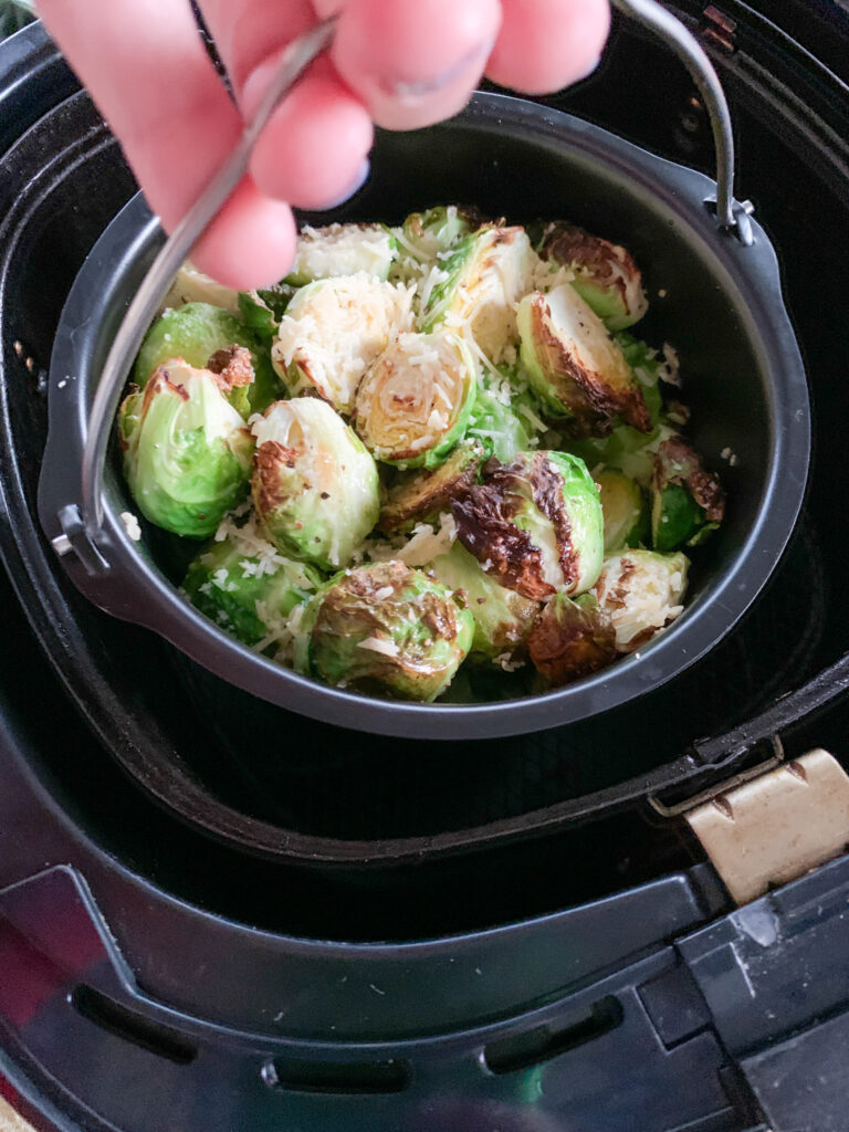 air fryer Brussels sprouts in air fryer skillet while woman holds handle
