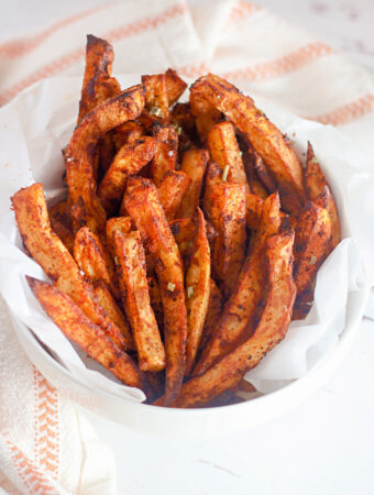 air fryer home fries in white serving bowl with tea towel beside