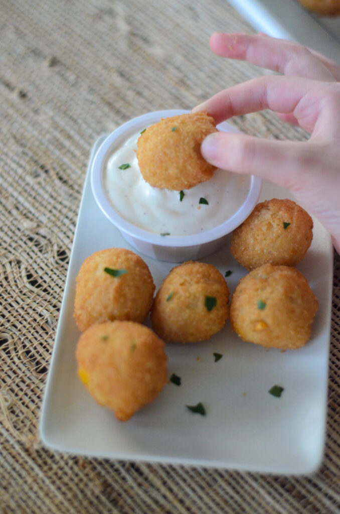 girl dips air fried hushpuppies in ranch dressing