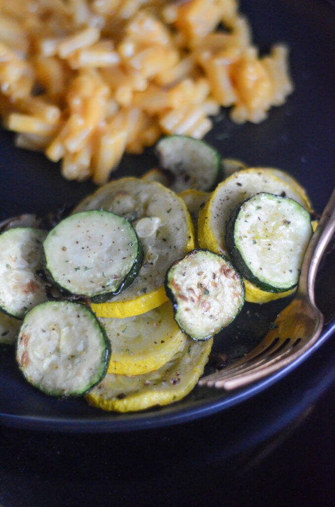air fryer squash and zucchini on black plate with mac and cheese in back