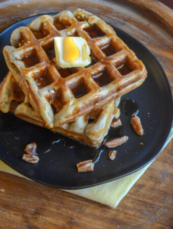 banana nut waffles on black plate on yellow napkin