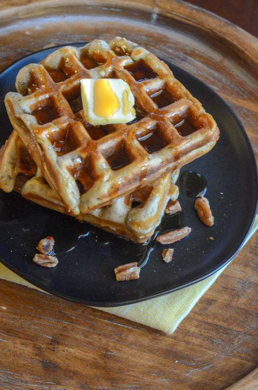 banana nut waffles stacked on black plate with yellow napkin underneath