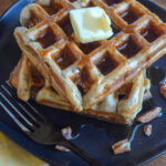 banana nut waffles on black plate with butter on top