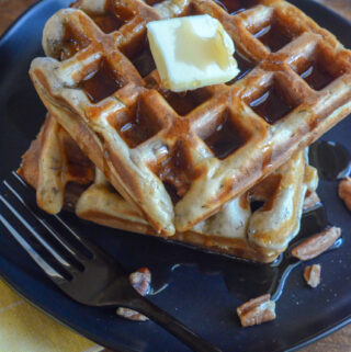 banana nut waffles on black plate with butter on top