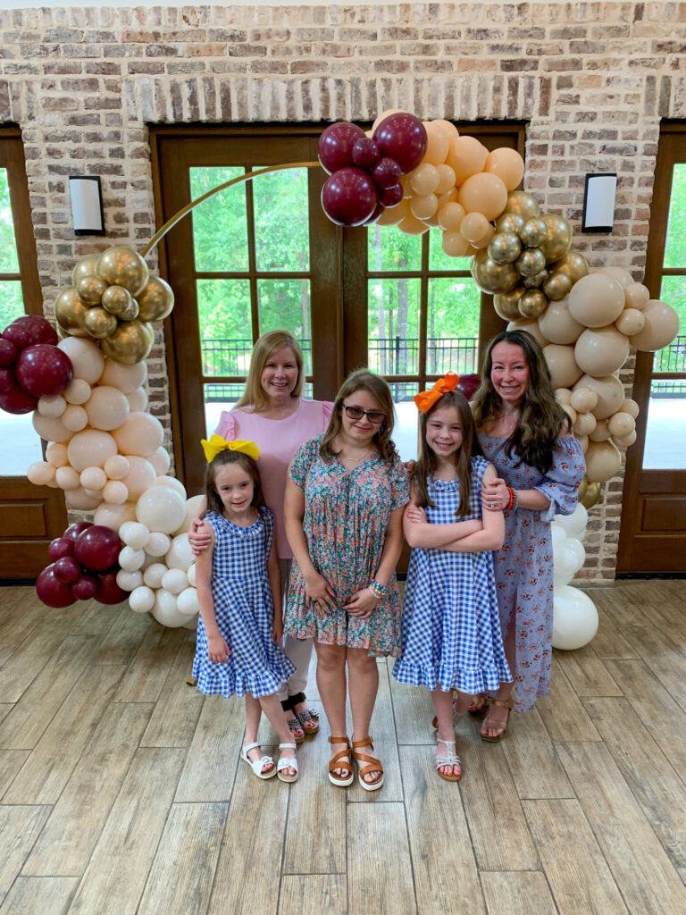 group stands in front of balloon arch at high school graduation party