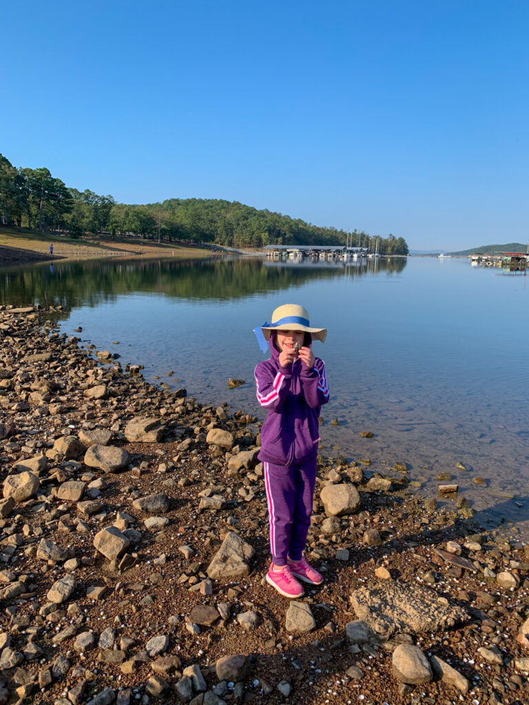 little girl dressed warmly on rocky area of shore at Lake Ouachita 