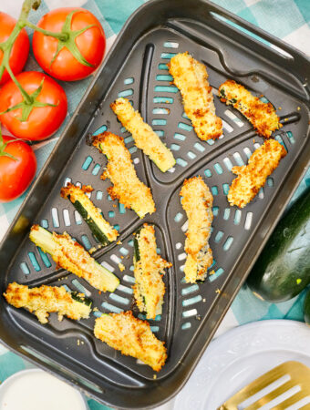 parmesan air fryer zucchini fries in pan with fresh veggies on side