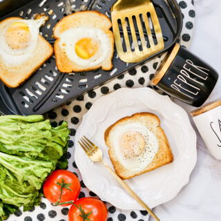air fryer egg on toast on white serving plate beside veggies