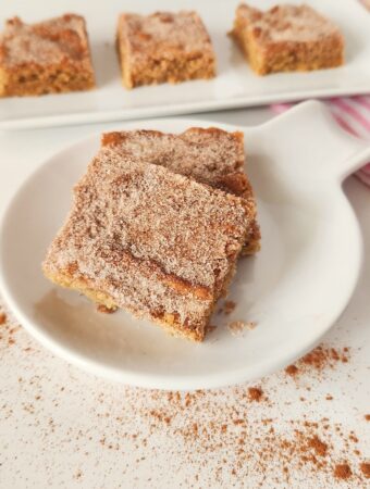 cinnamon churro bars stacked on round plate with more in back