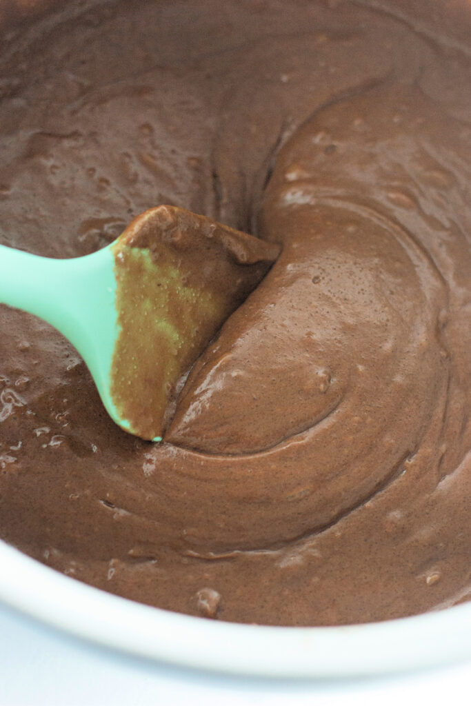 green spatula stirs batter in bowl