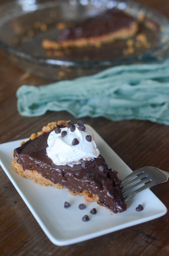 Jello chocolate pudding pie on a white plate with a fork to the side