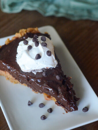 chocolate pudding pie on a white plate with chocolate chips scattered