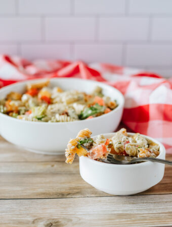 bacon cheddar pasta salad with ranch in two small white bowls with red napkin at back