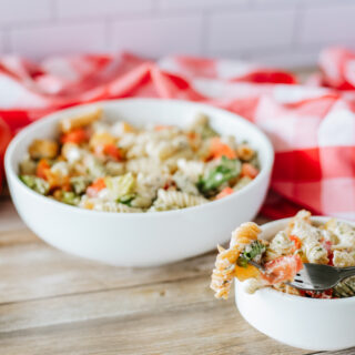 bacon and cheddar pasta salad in white bowls with plaid napkin