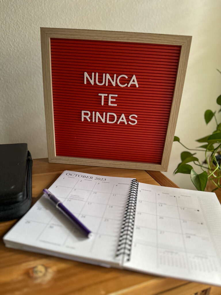 inspirational quotes in Spanish on red letter board with calendar in front