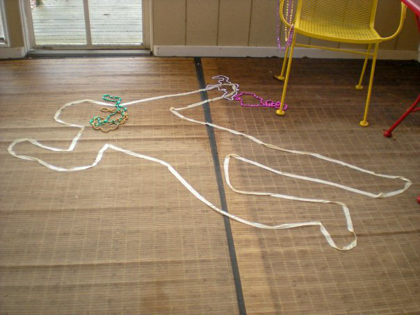 murder mystery dead body outline on floor with Mardi Gras beads around