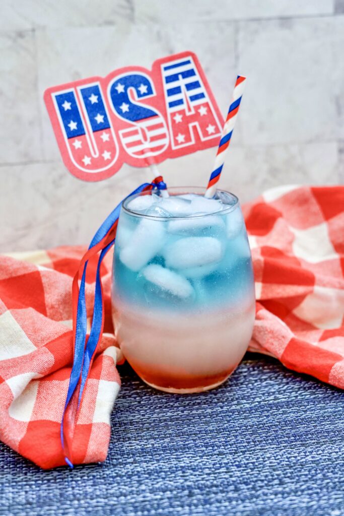 patriotic layered mocktail with grenadine for fourth of july drink with red napkin in back
