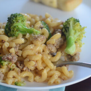 sausage broccoli macaroni on white plate with plaid napkin under