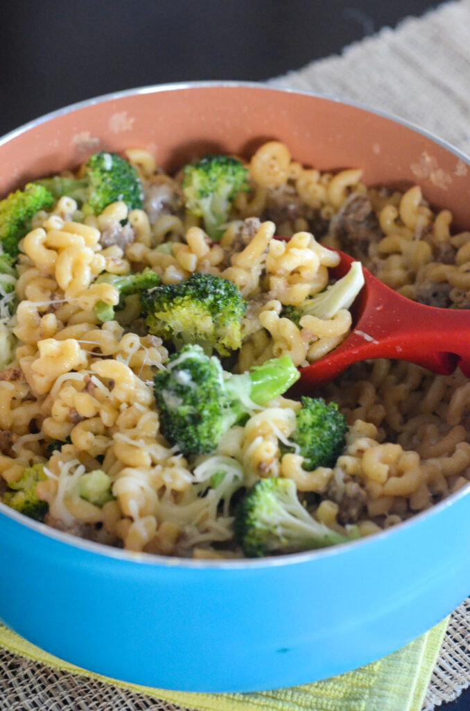 sausage broccoli macaroni in pan with red serving spoon