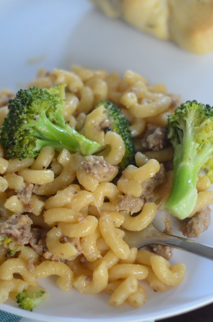 sausage broccoli macaroni on white plate with fork inserted