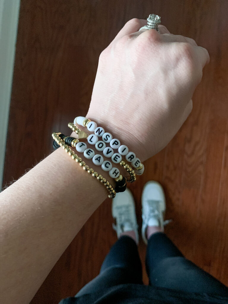 stacked teacher bracelet in white, black and gold on lady's hand