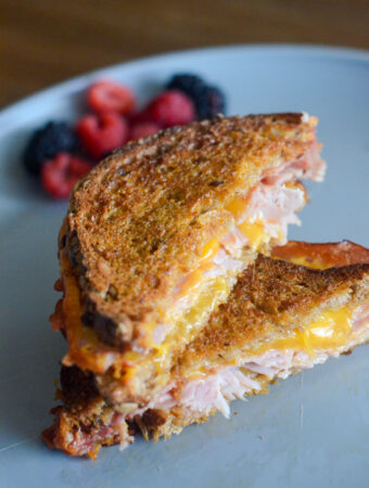 air fryer ham and cheese sandwich on grey plate with berries in back