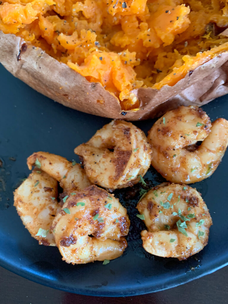 Cajun butter shrimp near potato on plate
