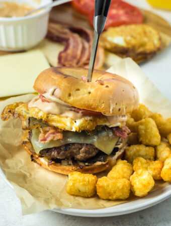 bagel burger for breakfast on plate with knife inserted