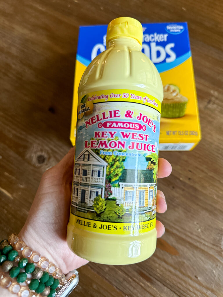 woman holds Nellie and Joes bottled lemon juice over box of graham cracker crumbs