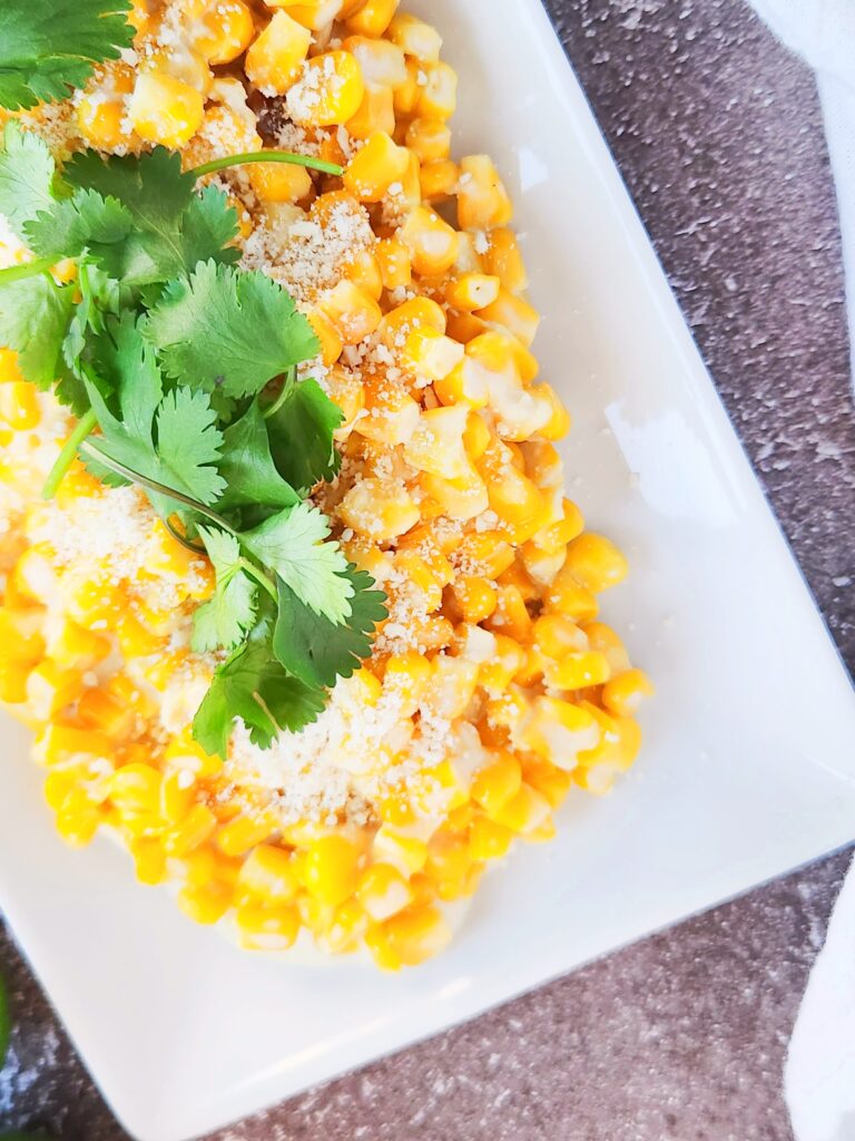 Crock Pot elote casserole on white serving plate with cilantro on top