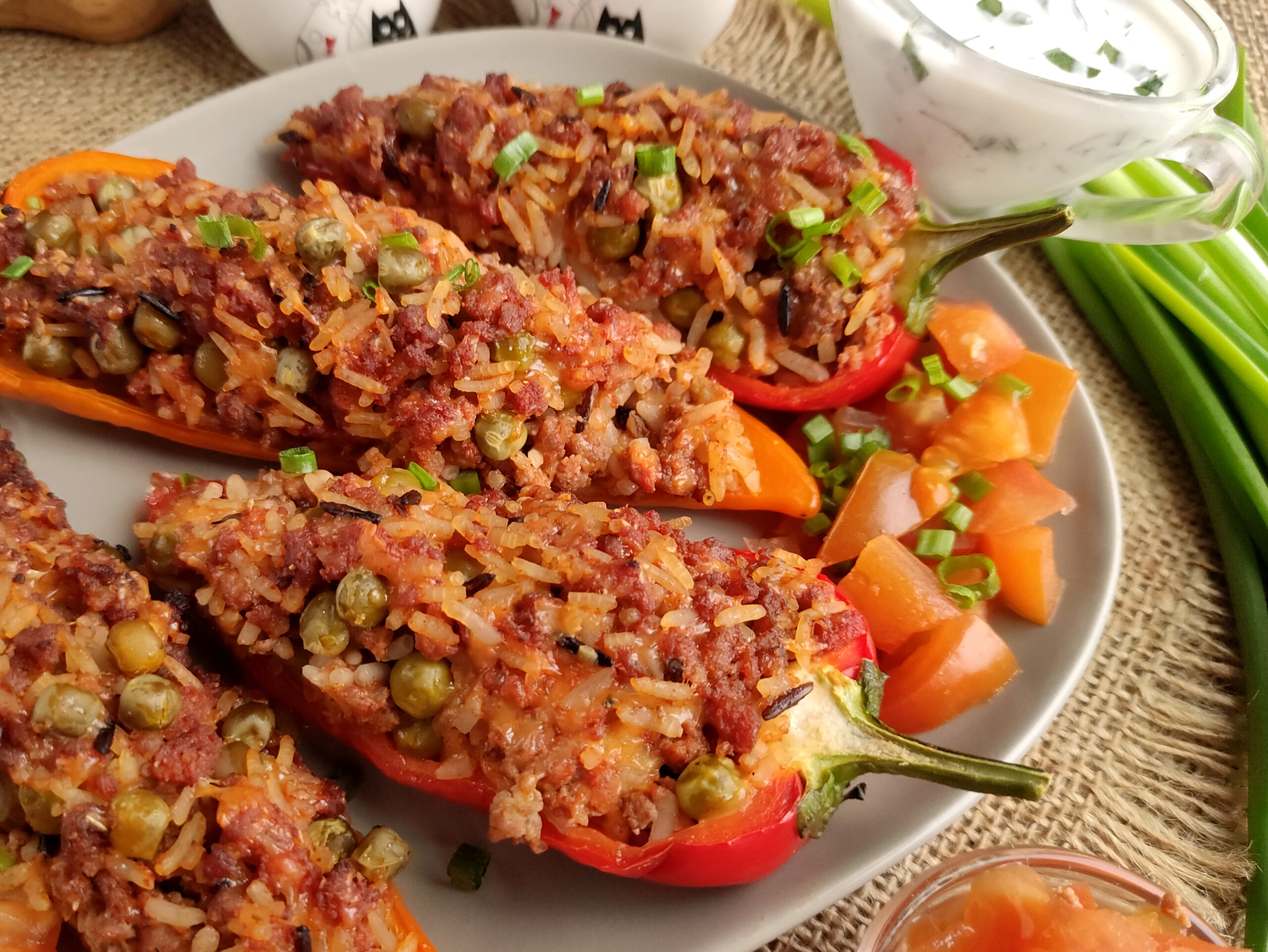 taco stuffed peppers on round platter with pile of chopped tomatoes