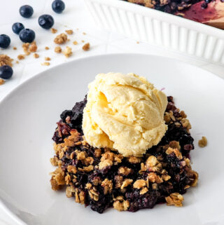 blueberry crisp with oats on a white rimmed plate