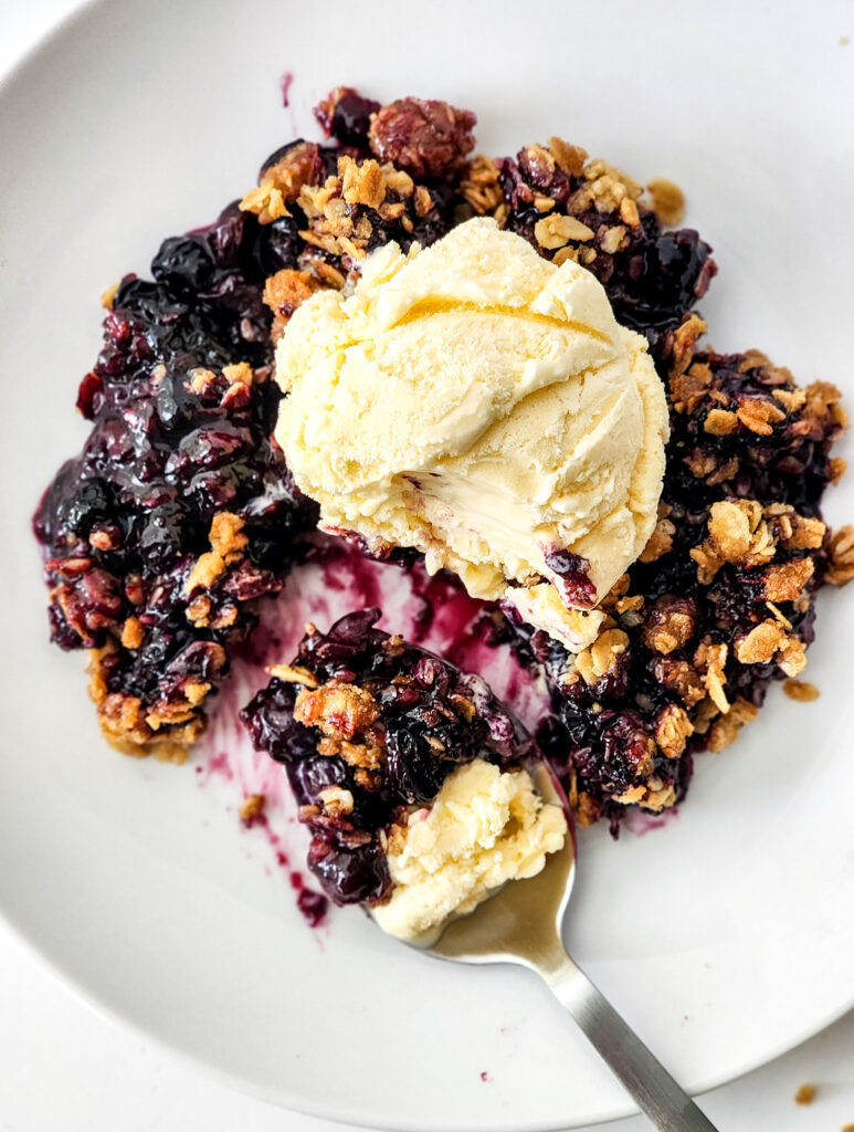 blueberry granola crisp with vanilla ice cream on top and spoonful to the side