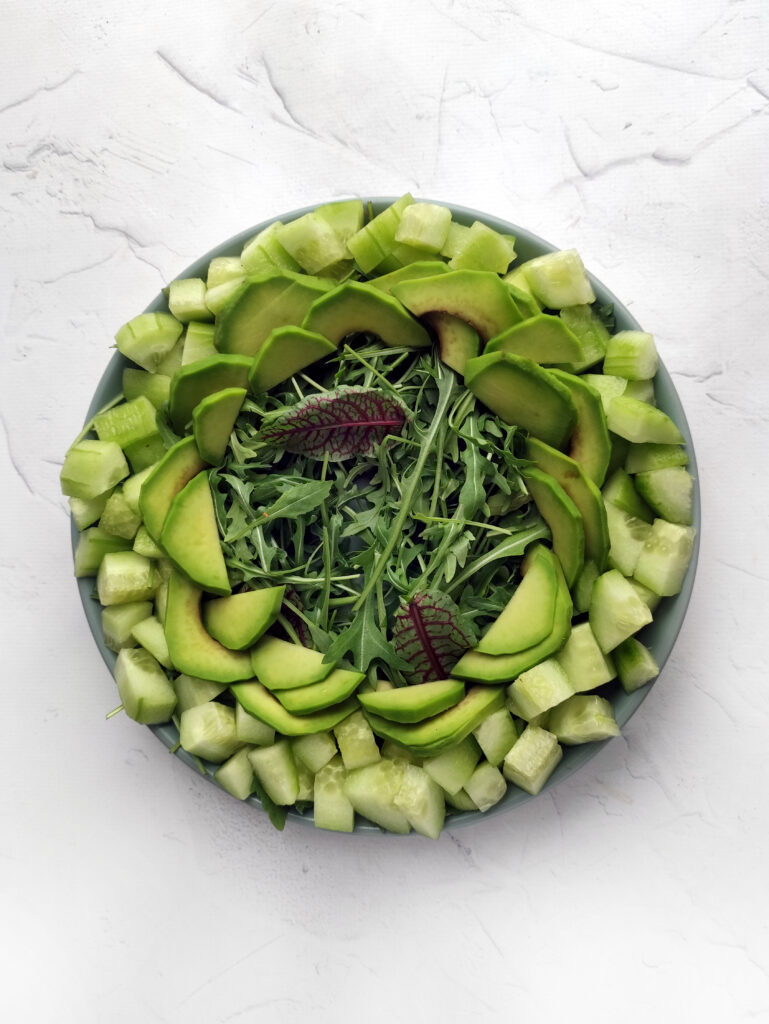spinach arugula salad with layers of veggies around the bottom