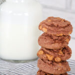 stacked butterscotch chocolate pudding cookies beside glass jug of milk