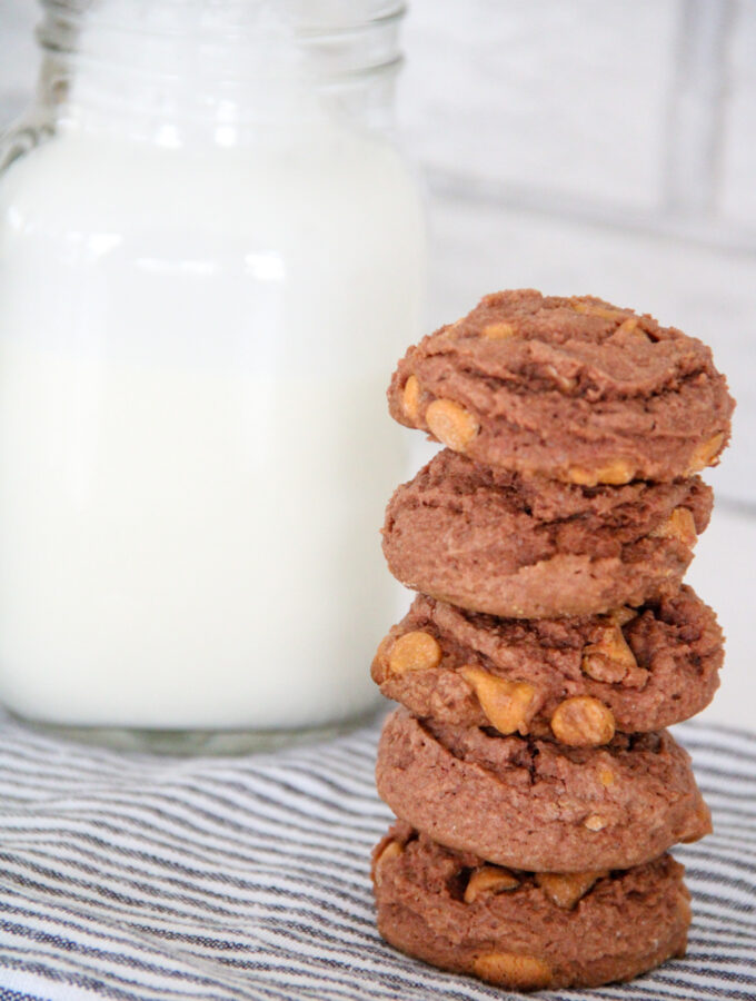 stacked butterscotch chocolate pudding cookies beside glass jug of milk