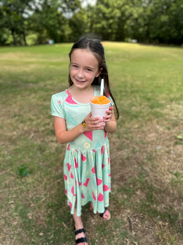 little girl smiles while holding snow cone from Candy's Snow Cones truck in Little Rock area