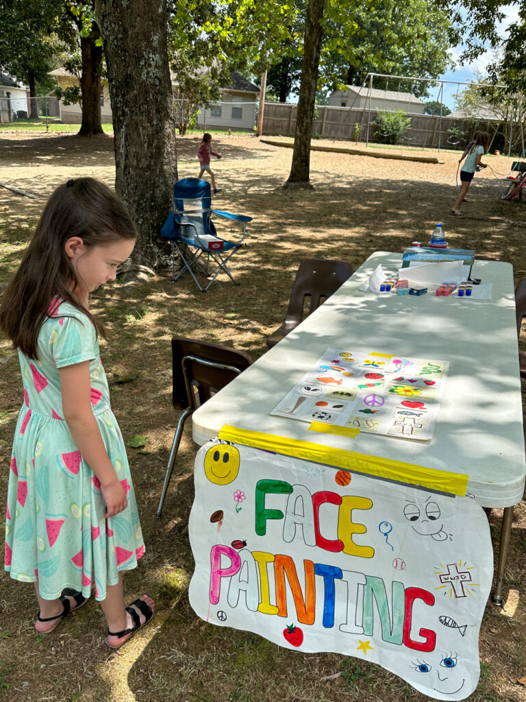 little girl looks at options for face painting for company picnic ideas