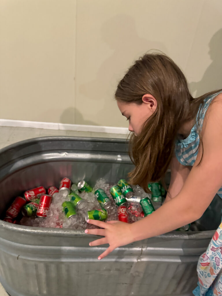 girl pulls drinks out of galvenized tub