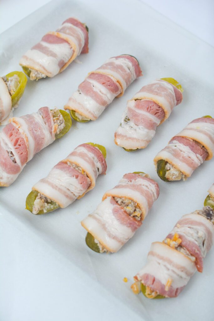bacon wrapped around pickle poppers with cheeseburger filling inside
