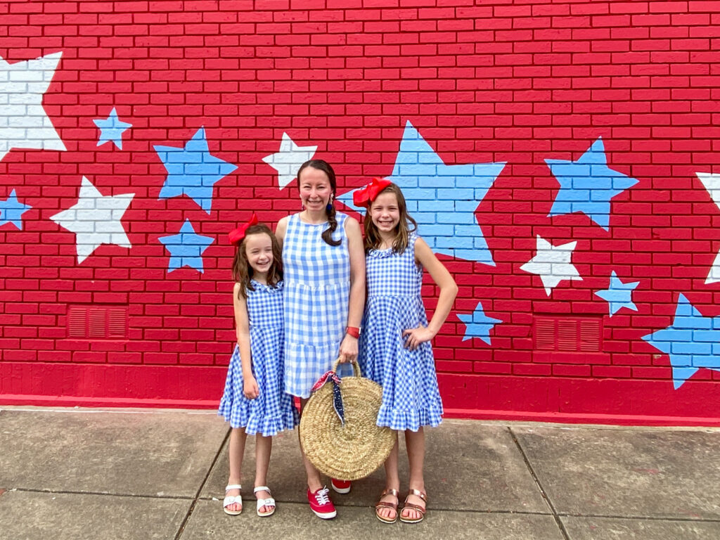 mom and girls wear mom and daughter matching 4th of July outfits in front of patriotic Benton, Arkansas mural