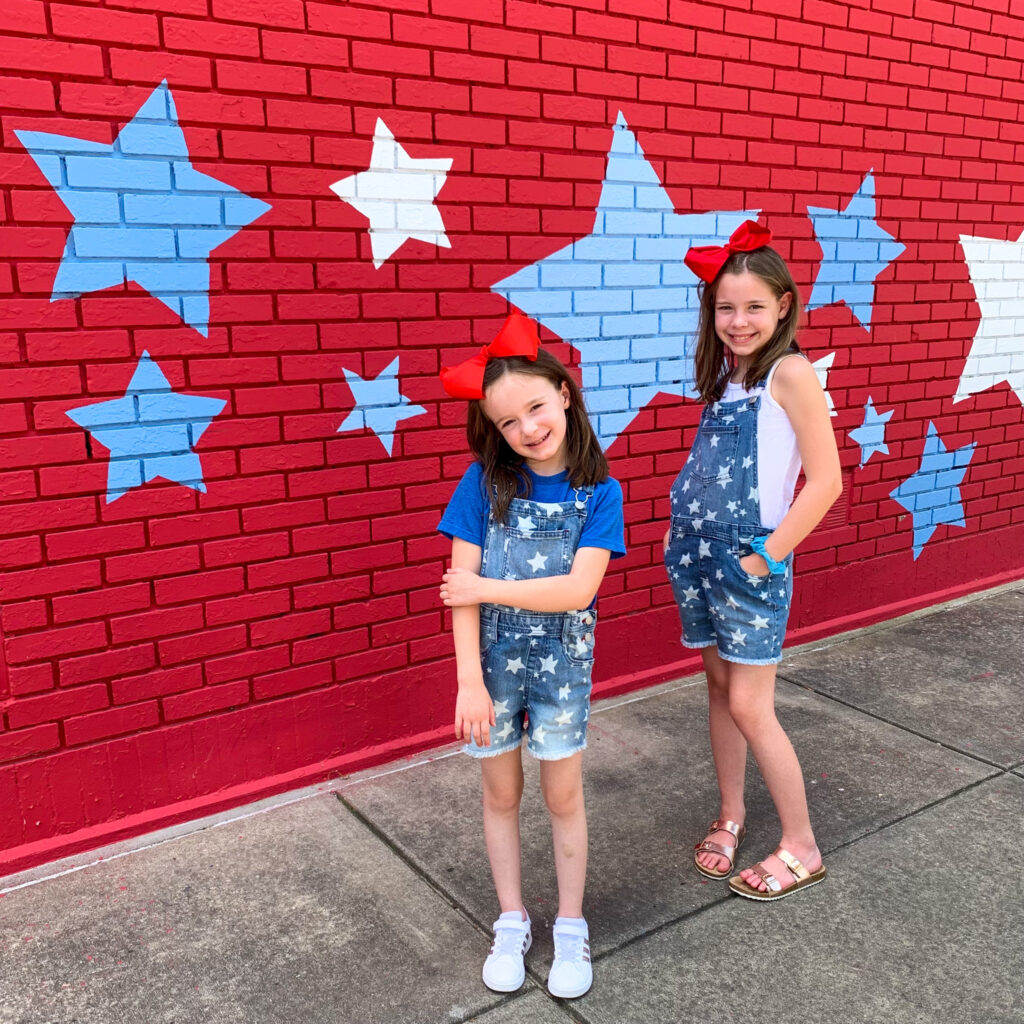 Arkansas lifestyle tween bloggers model patriotic girl outfits in front of star wall in Benton, Arkansas