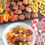 plate with kielbasa potato pepper bake with kielbasa sheet pan meal in pan at back