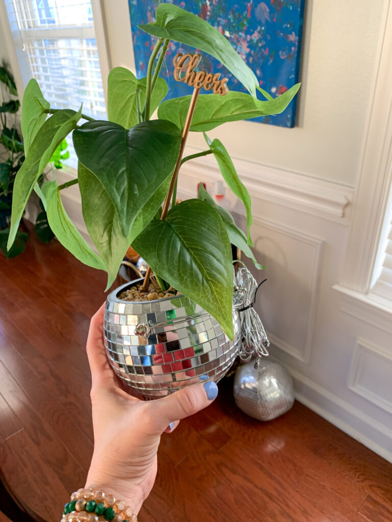 woman holds disco ball planter in front of a NYE bar cart